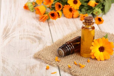 aromaterapi Uçucu yağı ile taze kadife çiçeği çiçek Beyaz ahşap zemin üzerinde. Calendula petrol