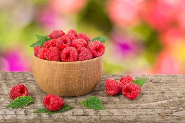 Ahududu bulanık bir bahçe arka plan ile tabloda bir ahşap kase