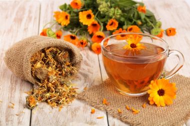 Calendula çay beyaz ahşap zemin üzerinde taze ve kurutulmuş çiçekli