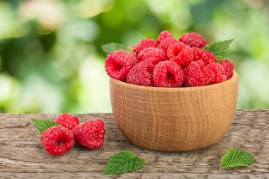 Ahududu bulanık bir bahçe arka plan ile tabloda bir ahşap kase