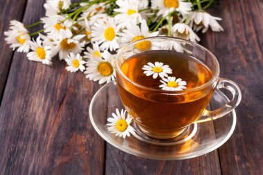 Siyah ahşap zemin üzerine taze papatya çiçeği ile bitkisel çay