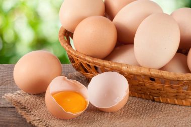 Bahçe arka plan bulanık ile ahşap bir gemide bir hasır sepet yumurta