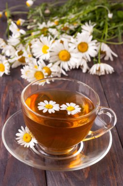 Siyah ahşap zemin üzerine taze papatya çiçeği ile bitkisel çay