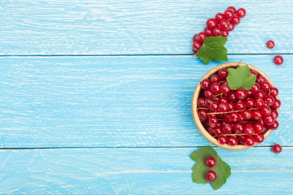 Frenk üzümü çilek yaprak mavi ahşap arka plan üzerinde ahşap bir kase. Üstten Görünüm