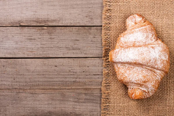 Um croissants polvilhado com açúcar em pó no fundo de madeira velho com espaço de cópia para o seu texto. Vista superior — Fotografia de Stock