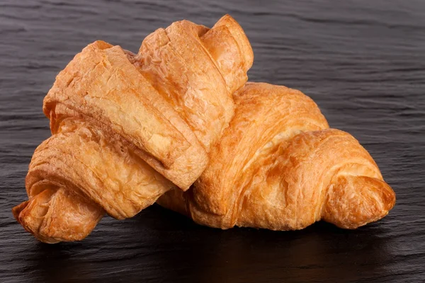 Zwei Croissants auf schwarzem Stein Hintergrund Nahaufnahme — Stockfoto