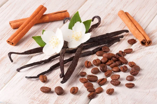 Palitos de vainilla y granos de café con canela sobre un fondo de madera blanca — Foto de Stock