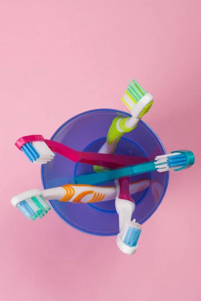 Toothbrushes in a blue plastic glass on a pink background — Stock Photo, Image