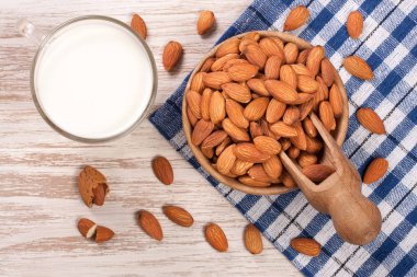 Bir cam ve hafif ahşap zemin üzerinde bir kasede badem badem sütü. Üstten Görünüm