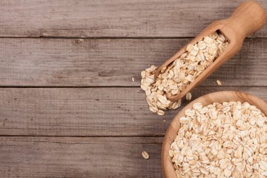 Metniniz için kopya alanı eski ahşap zemin üzerine bir kepçe ile ahşap bir kase yulaf gevreği. Üstten Görünüm