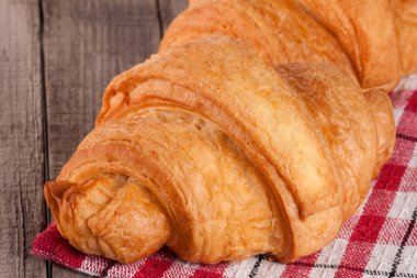 Bir peçete ile ahşap bir masa üzerinde bir kruvasan