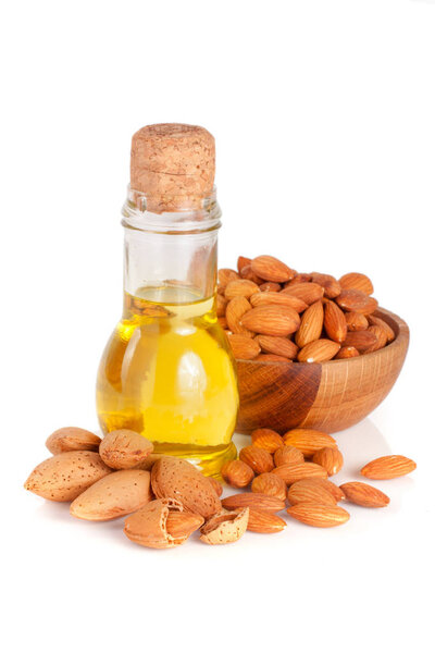 Bottle of almond oil and almonds in a wooden bowl isolated on white background