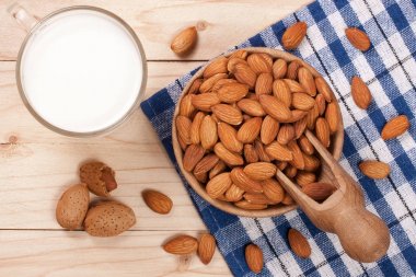 Bir cam ve hafif ahşap zemin üzerinde bir kasede badem badem sütü. Üstten Görünüm