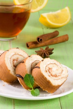 Bir fincan çay yeşil ahşap zemin üzerine ile bisküvi İsviçre rulo