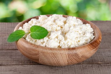 Bahçe arka plan bulanık gemide ahşap bir kase süzme peynir