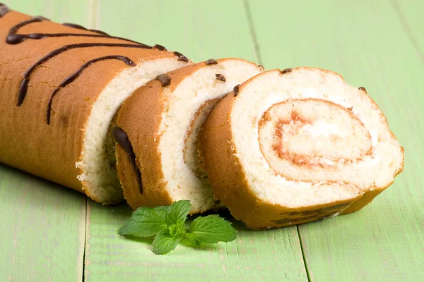 Biscuit swiss roll close-up on green wooden background — Stock Photo, Image