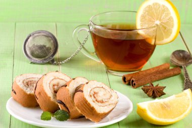 Bir fincan çay yeşil ahşap zemin üzerine ile bisküvi İsviçre rulo