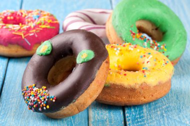 Mavi ahşap arka plan üzerinde sırlı donuts yığını