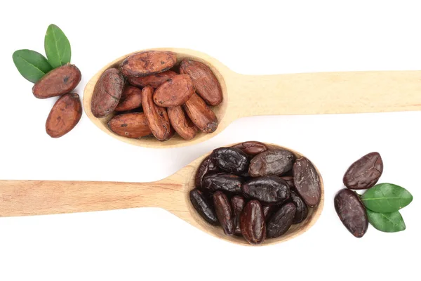 Granos de cacao pelados y sin pelar en una cuchara de madera con hoja aislada sobre fondo blanco vista superior — Foto de Stock