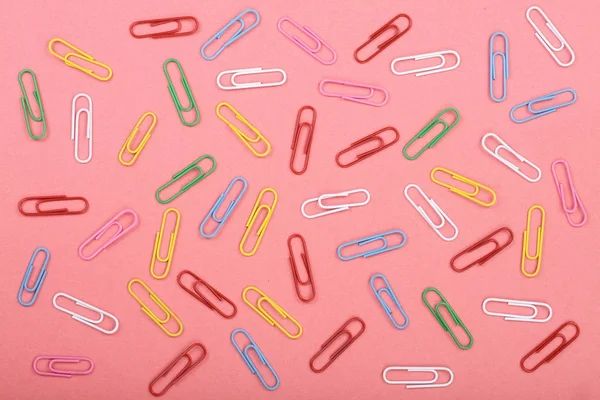 colorful paper clips on red background. Top view. Flat lay pattern
