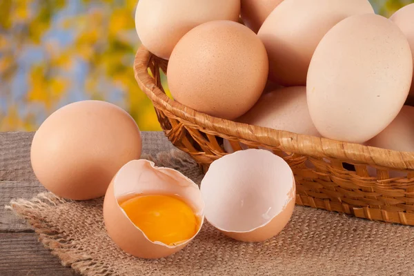 Eieren in een rieten mand op een houten bord met onscherpe achtergrond van de tuin — Stockfoto