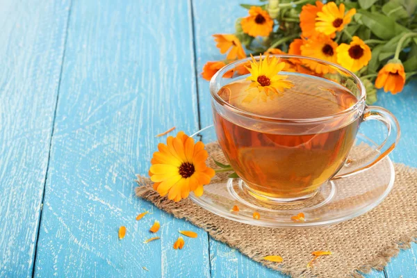 Calendula tea with fresh flowers on blue wooden background — Stock Photo, Image