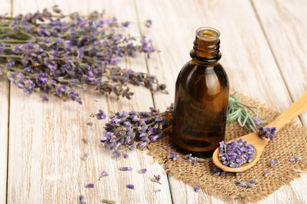 Óleo de ervas e flores de lavanda em fundo de madeira — Fotografia de Stock