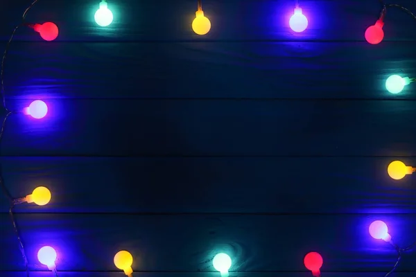 Luces de guirnalda de Navidad sobre fondo de madera oscura con espacio de copia para su texto. Vista superior — Foto de Stock