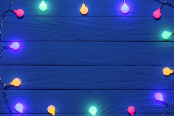 Ghirlanda di Natale luci su sfondo blu in legno con spazio copia per il testo. Vista dall'alto — Foto Stock