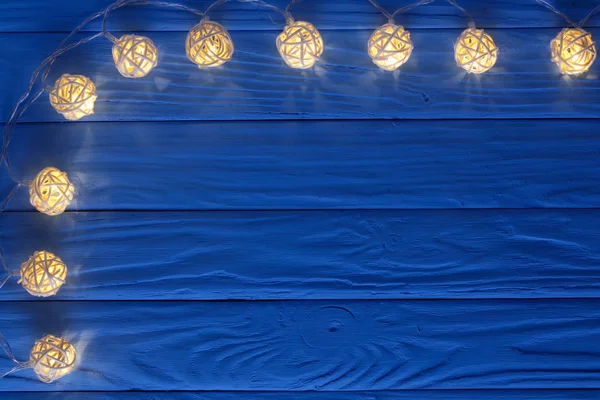 Guirlande de Noël lumières sur fond bleu en bois avec espace de copie pour votre texte. Vue du dessus — Photo