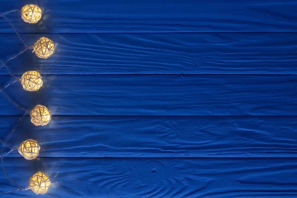 テキストのコピー スペースと青い木製の背景にクリスマス ガーランド ライト。トップ ビュー — ストック写真