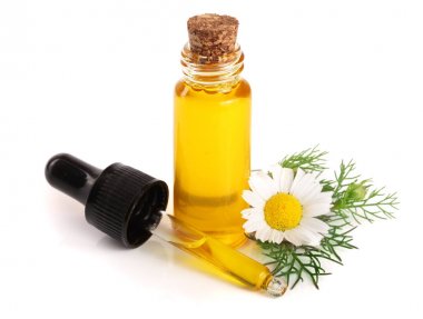 Beyaz arka planda özgün yağ ve taze papatya çiçekleri bulunan şişe.