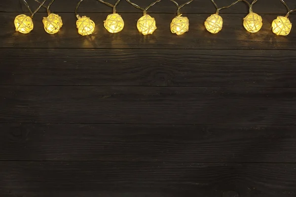 Christmas garland lights på svart trä bakgrund med kopia utrymme för din text. Ovanifrån — Stockfoto
