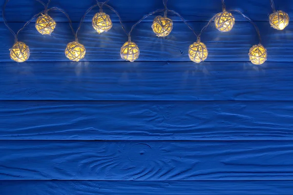 Luces de guirnalda de Navidad sobre fondo de madera azul con espacio de copia para su texto. Vista superior —  Fotos de Stock
