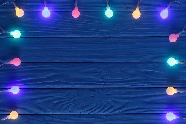 Рождественские гирлянды огни на синем деревянном фоне с копировальным пространством для текста. Вид сверху — стоковое фото