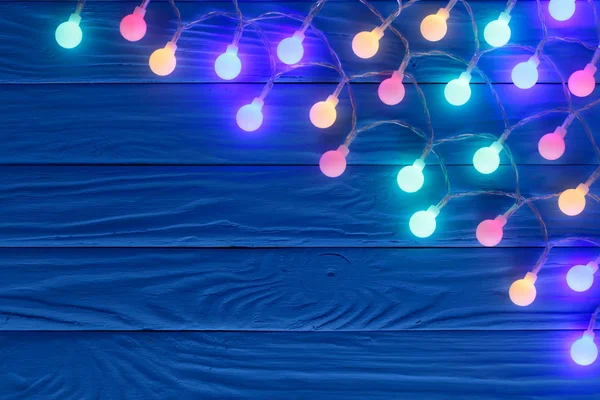 テキストのコピー スペースと青い木製の背景にクリスマス ガーランド ライト。トップ ビュー — ストック写真