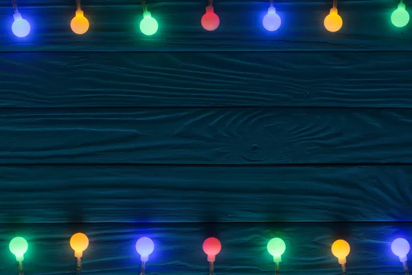 Χριστουγεννιάτικη γιρλάντα ανάβει μπλε φόντο ξύλινη με αντίγραφο χώρου για το κείμενό σας. Το Top view — Φωτογραφία Αρχείου