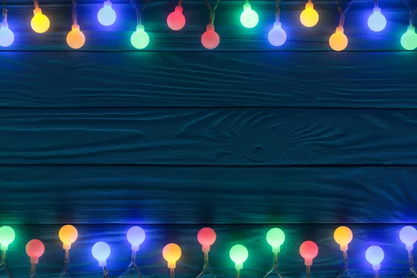 Різдвяні гірлянди вогні на синьому дерев'яному фоні з копіювальним простором для вашого тексту. Вид зверху — стокове фото