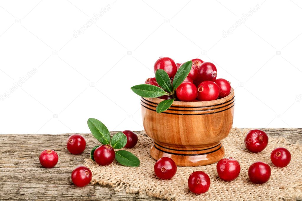 Cranberry with leaf in wooden bowl on old wooden table with white background