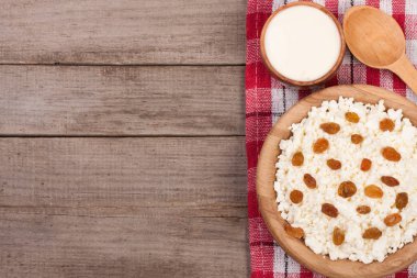 Ekşi krema ve kopya alanı metniniz için eski ahşap zemin üzerine kuru üzüm kase süzme peynir. Üstten Görünüm