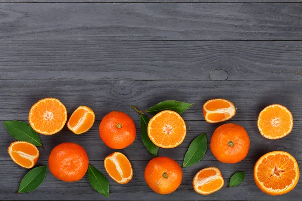 tangerine with leaves on black wooden background with copy space for your text. Flat lay, top view. Fruit composition