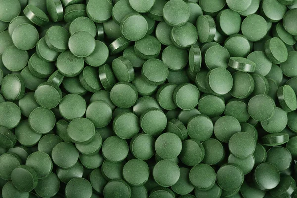 Amontoado de comprimidos Spirulina algas suplemento nutricional como um fundo close-up vista superior. Depósito plano — Fotografia de Stock