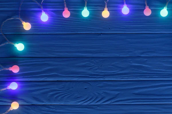 Luces de guirnalda de Navidad sobre fondo de madera azul con espacio de copia para su texto. Vista superior — Foto de Stock