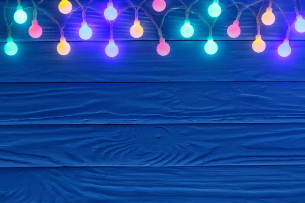 Χριστουγεννιάτικη γιρλάντα ανάβει μπλε φόντο ξύλινη με αντίγραφο χώρου για το κείμενό σας. Το Top view — Φωτογραφία Αρχείου