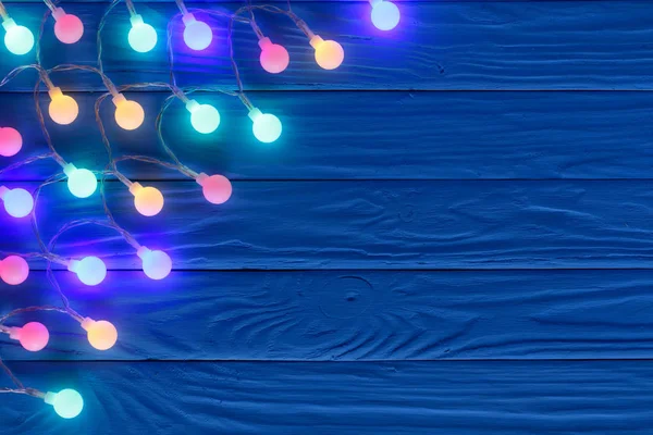 Kerstverlichting garland op blauwe houten achtergrond met kopie ruimte voor uw tekst. Bovenaanzicht — Stockfoto