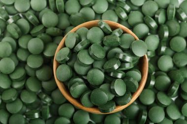 yığın Spirulina yosun besin takviyesi ahşap kase içinde en iyi görünümü kadar yakın arka plan olarak tablet. Düz yatıyordu