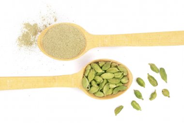 Yeşil kakule tohumu ve beyaz arka plan üzerinde izole bir tahta kaşık toz. Üstten Görünüm. Yat