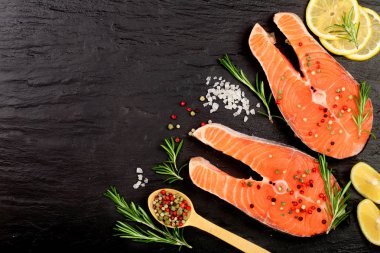 Dilim limon ile kırmızı balık somon, biberiye, metniniz için kopya alanı siyah taş zemin üzerine. Üstten Görünüm