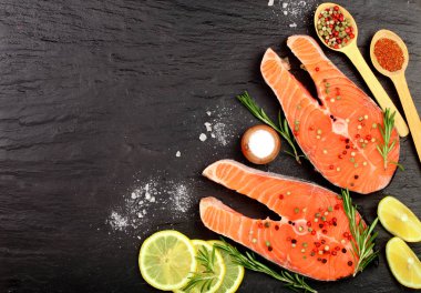 Dilim limon ile kırmızı balık somon, biberiye, metniniz için kopya alanı siyah taş zemin üzerine. Üstten Görünüm