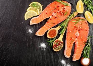 Dilim limon ile kırmızı balık somon, biberiye, metniniz için kopya alanı siyah taş zemin üzerine. Üstten Görünüm